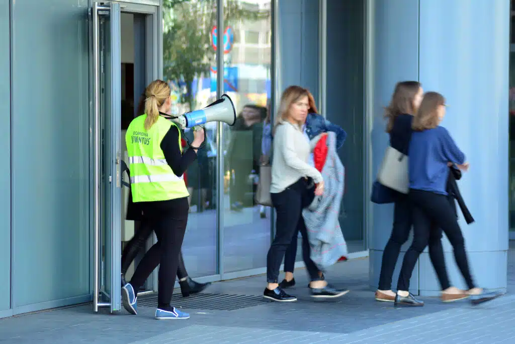 Employés de bureau portant des gilets fluorescents lors d'un exercice d'évacuation incendie.